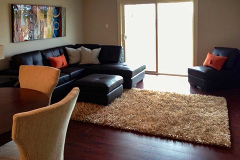 A living room with a black couch and a brown rug.