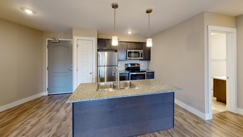 A kitchen with a granite countertop and stainless steel appliances.