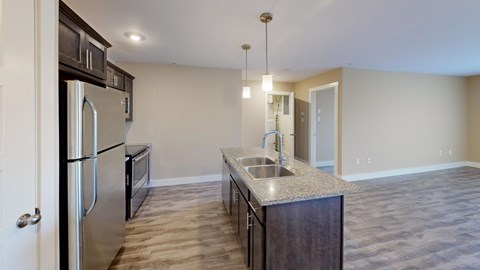 A kitchen with a refrigerator, sink, and cabinets.