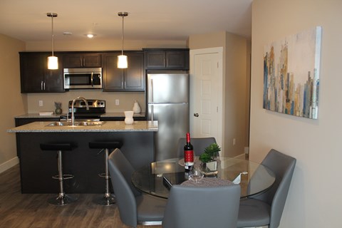 A kitchen with a bar and chairs.