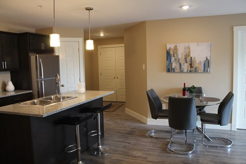 A kitchen with black cabinets and a black bar stool.