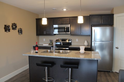 A kitchen with a granite counter top and stainless steel appliances.