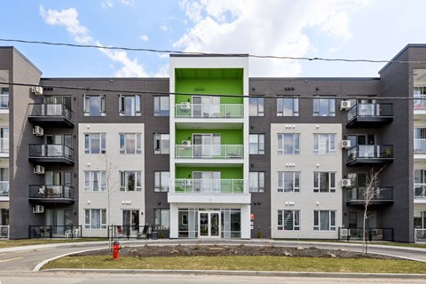 A large apartment building with a green and white section in the middle.