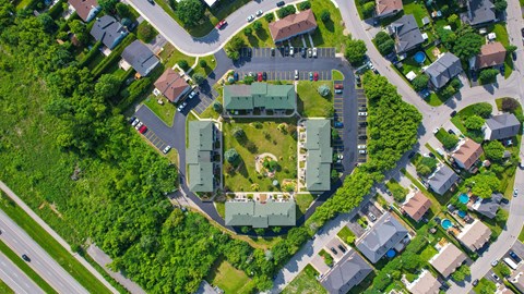 A bird's eye view of a residential area with houses and a large green building in the center.