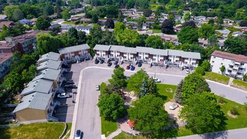 A bird's eye view of a residential area with houses, a park, and a parking lot.