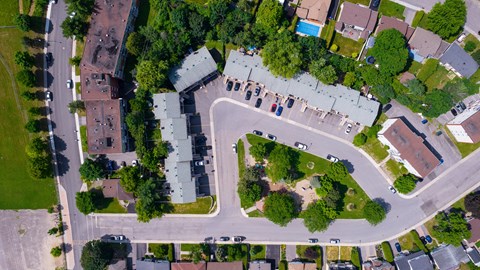 A bird's eye view of a residential area with houses, trees, and roads.