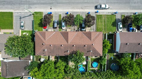 A large building with a brown roof is surrounded by trees and has a pool in front.