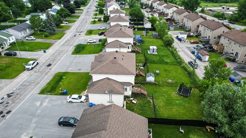 A residential street with houses on both sides and cars parked on the street.