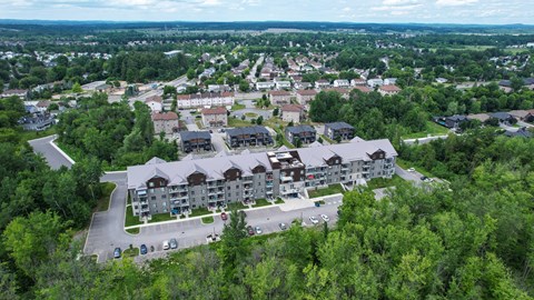 A bird's eye view of a residential area with apartment buildings surrounded by trees.