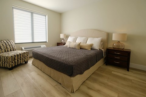 A bedroom with a large bed and a chair.