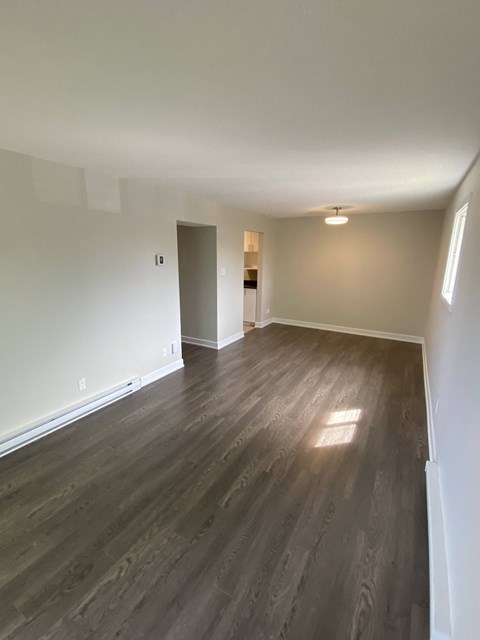A room with wooden flooring and a door on the left.