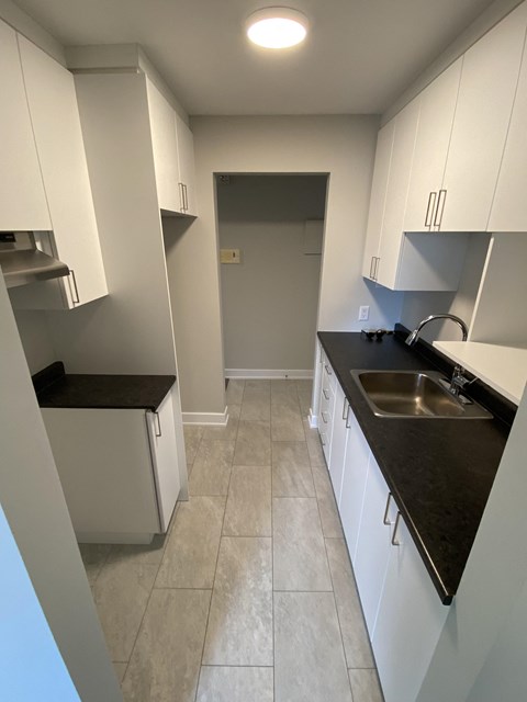 A kitchen with white cabinets and a black countertop.
