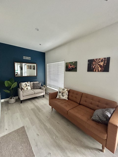 A living room with a brown couch and a mirror on the wall.