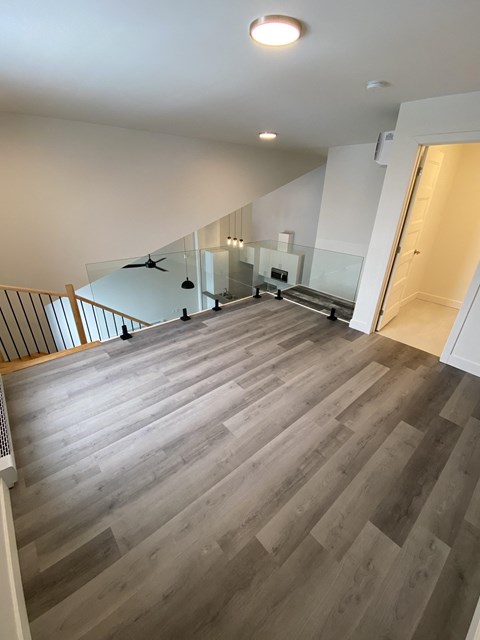 A spacious room with a staircase and a glass railing.