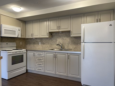 A kitchen with white appliances and cabinets.