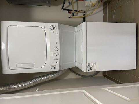 A white dryer is installed in a wall.