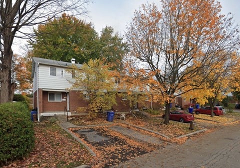 A house with a driveway and trees with orange leaves.