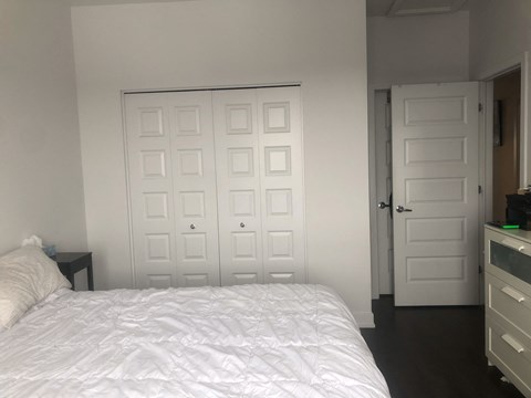 A white bed with a white comforter and pillow in a white room.