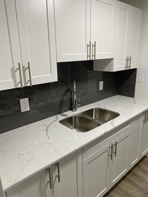 A kitchen with white cabinets and a marble countertop.
