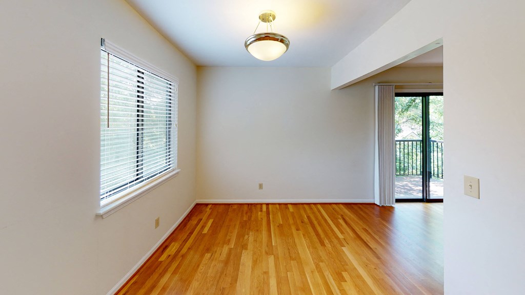 an empty living room with wood floors and a large window
