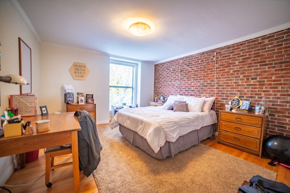 a bedroom with a bed and a brick wall