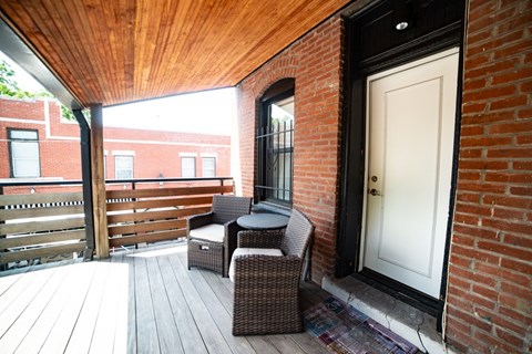 A patio with a white door and a brown wicker chair.