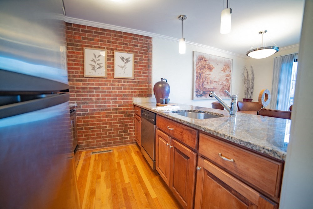 a kitchen with a sink and a counter top and a brick wall