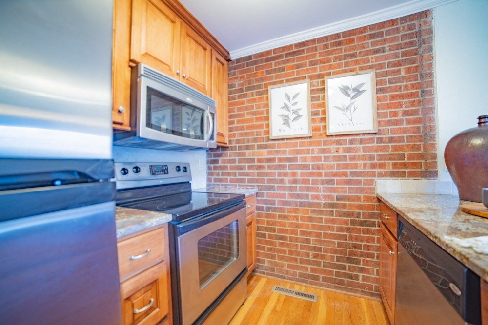 a kitchen with stainless steel appliances and a brick wall