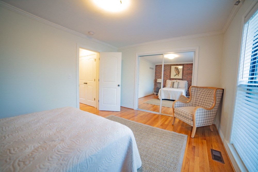 a bedroom with a bed and a chair and a mirror