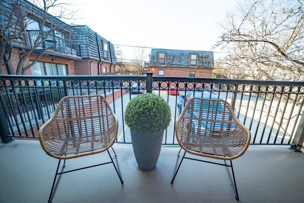 a balcony with two chairs and a potted plant on it