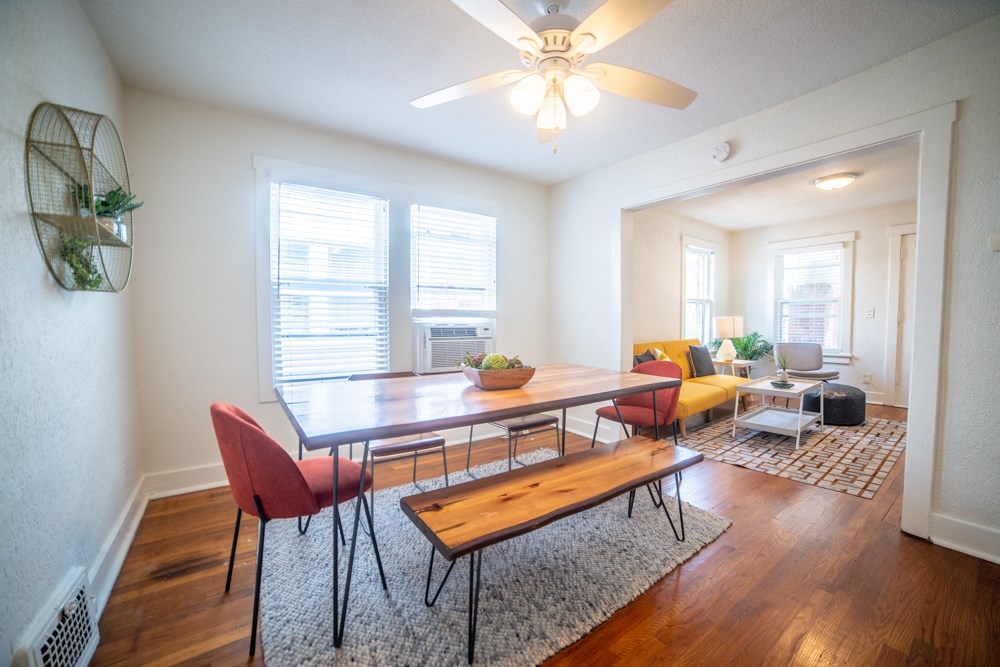 a living room with a dining room table and a ceiling fan