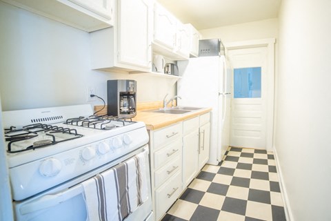 a kitchen with white appliances and a checkered floor