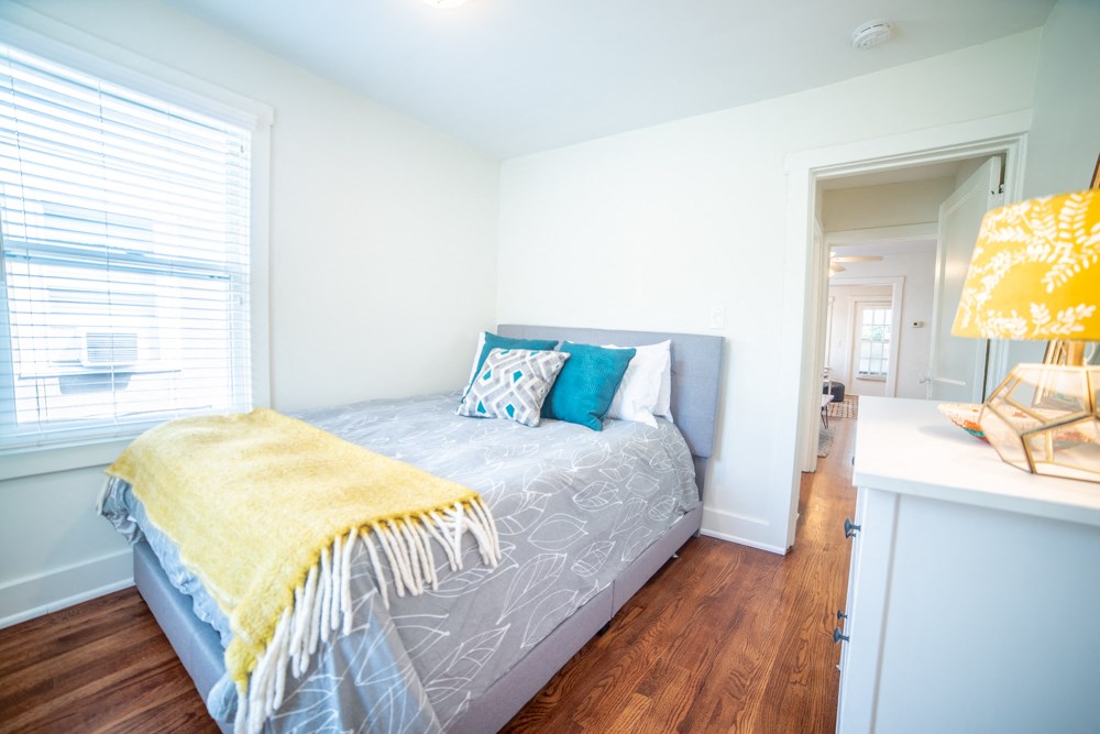 a bedroom with a bed with a yellow blanket and pillows