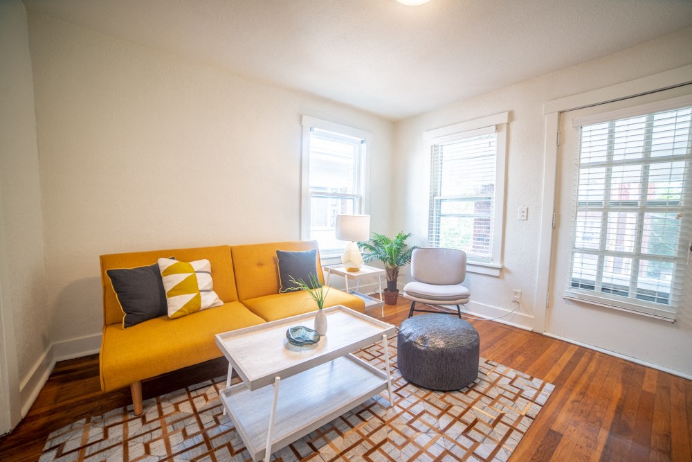 a living room with a yellow couch and a coffee table