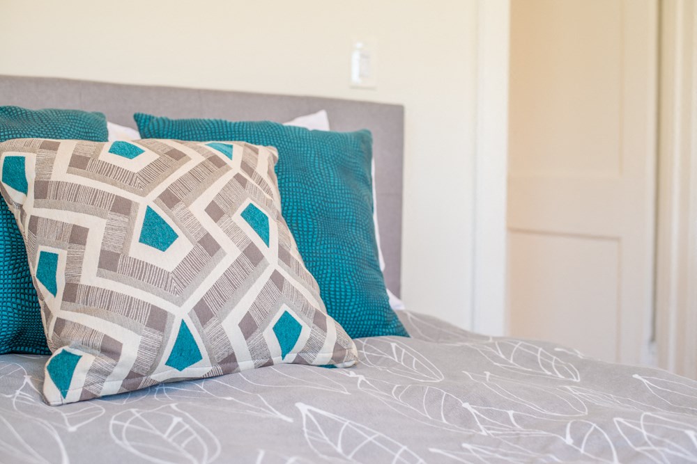 a bed with blue pillows and a grey comforter on it