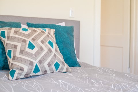 a bed with blue pillows and a grey comforter on it