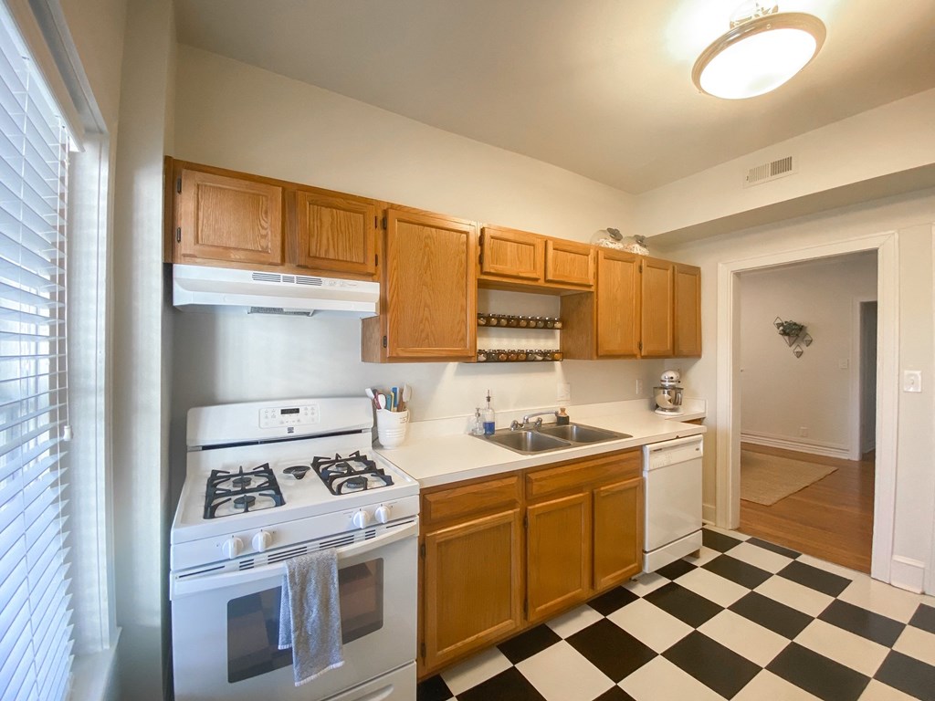 full kitchen with white appliances and wooden cabinets and checkered floor