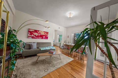 A living room with a grey couch and a red and white painting on the wall.