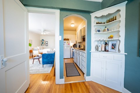 A kitchen with a blue wall and white cabinets.