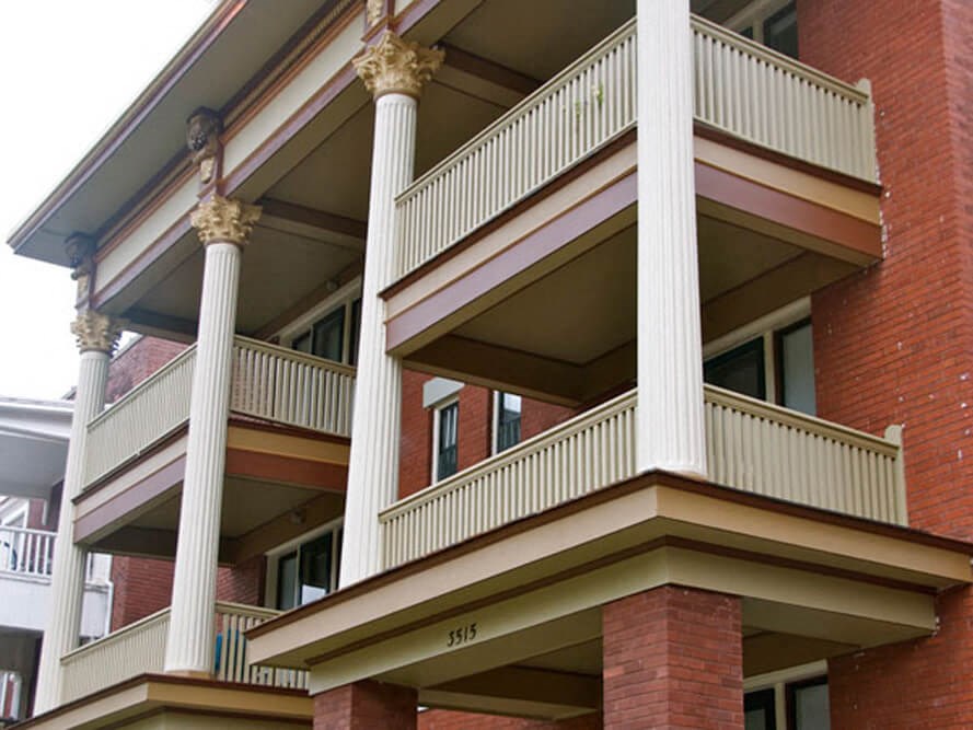 a red brick building with a balcony and columns