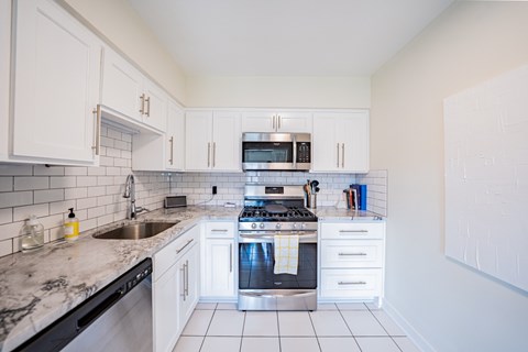 A kitchen with white cabinets and a black dishwasher.