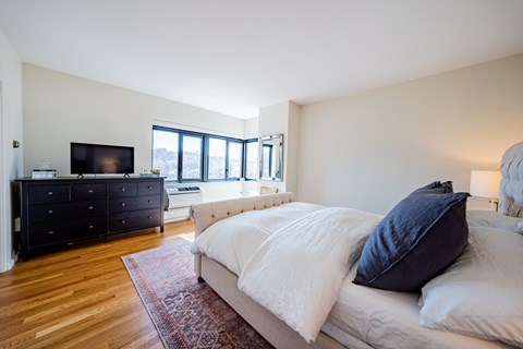 A bedroom with a large bed and a dresser with a flat screen TV on top.
