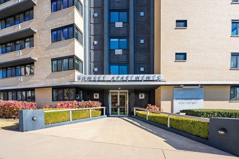 The image shows the front of a building with the sign "Sunset Apartments" on it.