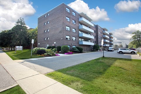 A large brick building with a green lawn in front.