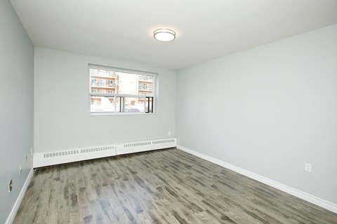 A room with a window and a radiator on the floor.