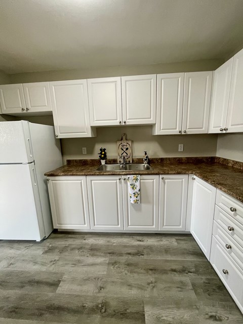 A kitchen with white cabinets and a white refrigerator.