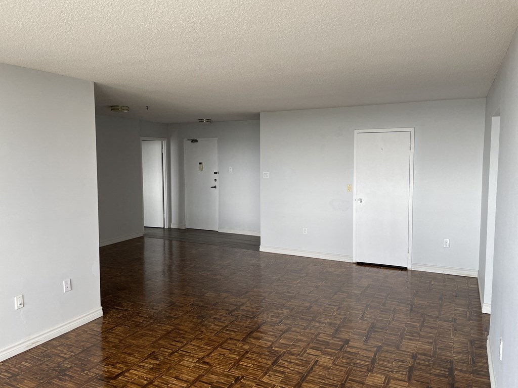 an empty living room with a wood floor and white walls
