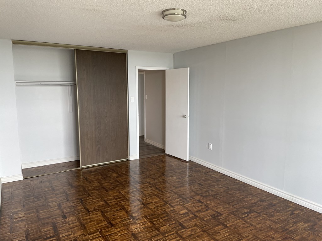 an empty living room with wood flooring and a closet