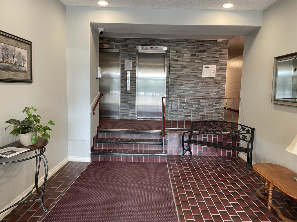 an elevator lobby with a bench and a brick wall in a building