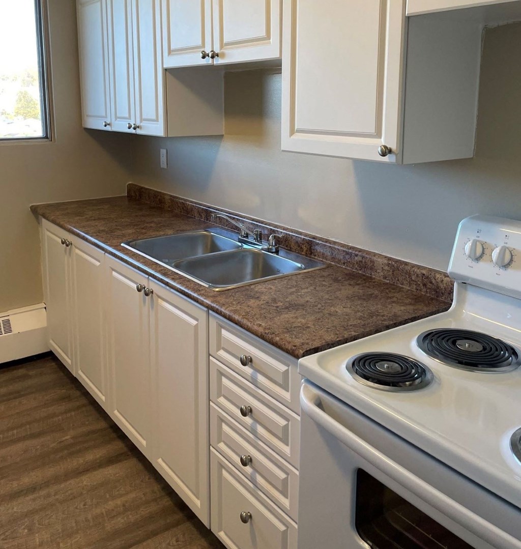 A kitchen with white cabinets and a white stove.